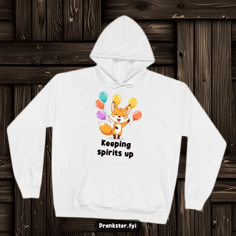 Funny hoodie depicting a happy fox character juggling a vibrant array of balloons with a wide, cheerful smile.